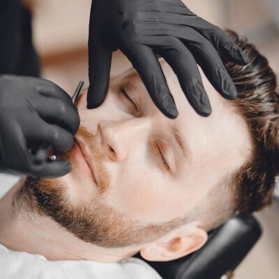 Barbershop. Hairdressers barber hair and beard with razor in salon.